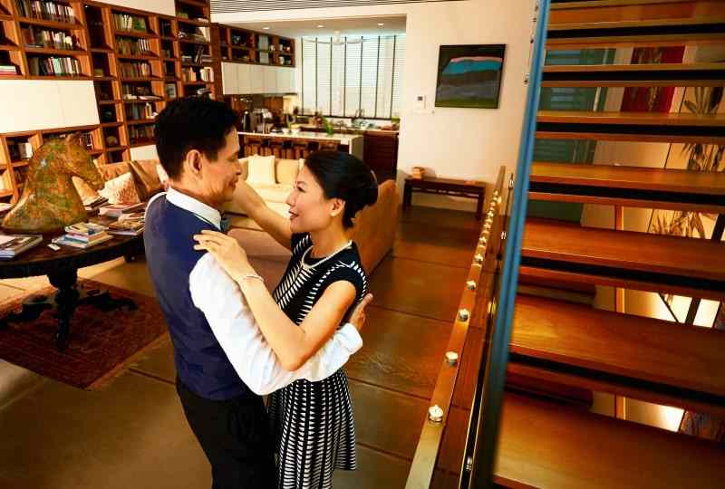 Wealth Mastery – rich Asian couple dancing at luxurious home